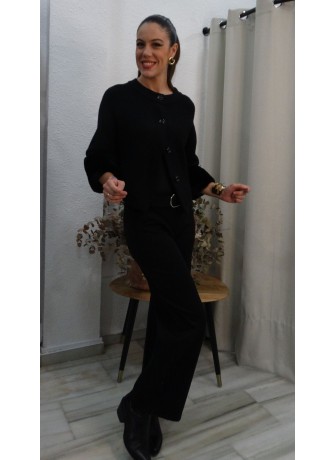 Modelo posando con chaqueta negra de punto con puños de pelo sintético, botones frontales y cuello redondo.