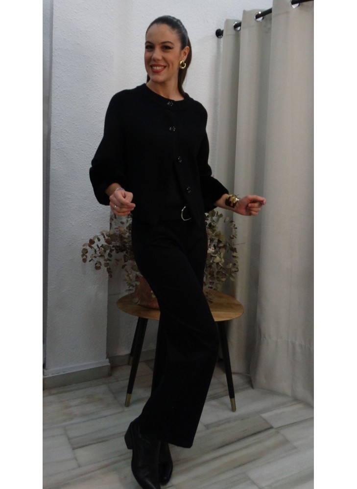 Modelo posando con chaqueta negra de punto con puños de pelo sintético, botones frontales y cuello redondo.