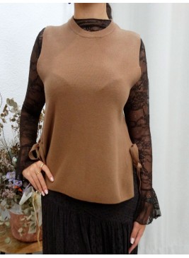 Modelo posando con chaleco cerrado en color camel, apertura en los lados con lazos en el mismo tono.