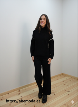 Modelo posando con jersey de punto negro de cuello perkins y adorno de raya blanca en espalda y parte superior de las mangas