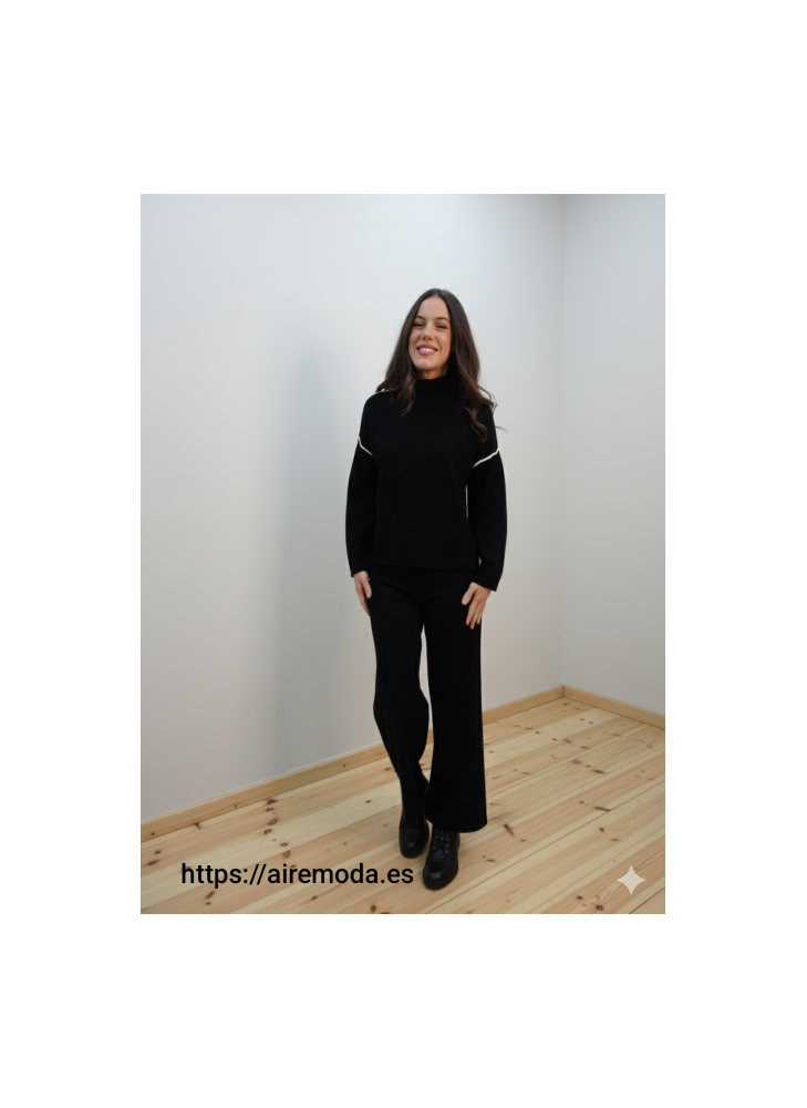 Modelo posando con jersey de punto negro de cuello perkins y adorno de raya blanca en espalda y parte superior de las mangas