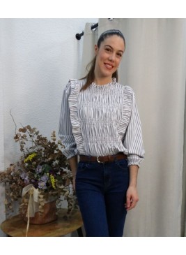 Mujer luciendo blusa manga larga de rayas diplomáticas en gris y con pecho fruncido y detalles de volantes laterales
