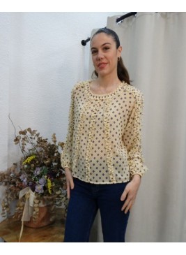 Mujer posando con blusa de gasa color crema con estampado de rombos y detalles de volantes verticales