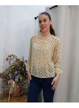 Mujer posando con blusa de gasa color crema con estampado de rombos y detalles de volantes verticales