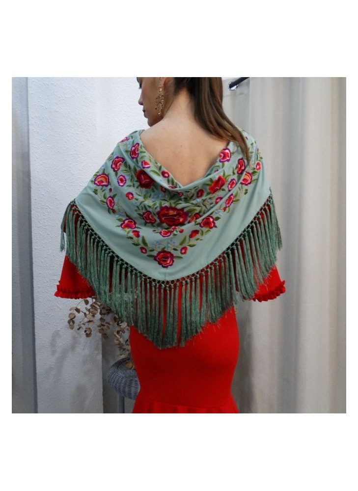 Modelo posando con mantón de flamenca color verde agua, bordado de rosas rojas y flecado a mano