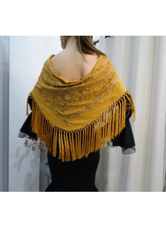Modelo posando con mantón de flamenca color mostaza bordado en el mismo tono y flecado a mano