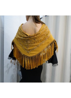Modelo posando con mantón de flamenca color mostaza bordado en el mismo tono y flecado a mano