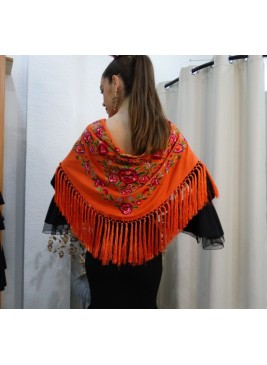 Modelo posando con mantón de flamenca en color butano con motivos florales en colores rosas, verdes y azul cielo