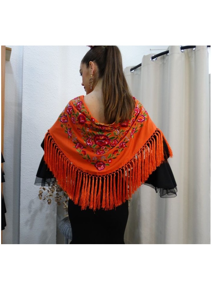 Modelo posando con mantón de flamenca en color butano con motivos florales en colores rosas, verdes y azul cielo