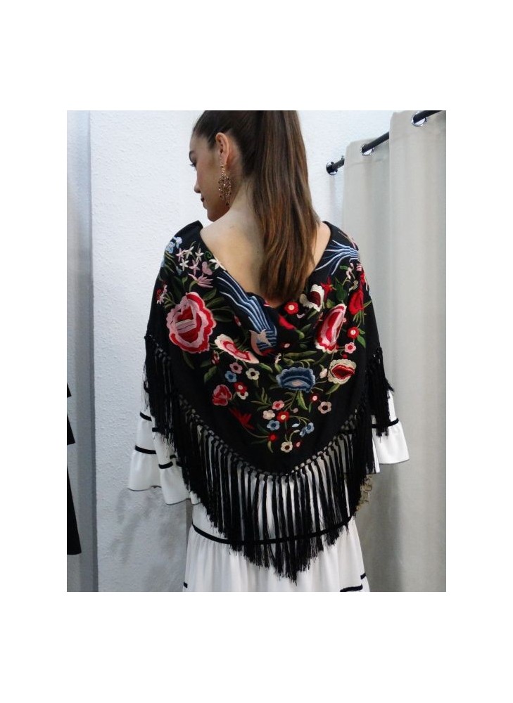 Modelo posando con mantón de flamenca color negro con bordados florales en tonos rosa, rojo y azul