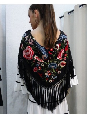 Modelo posando con mantón de flamenca color negro con bordados florales en tonos rosa, rojo y azul