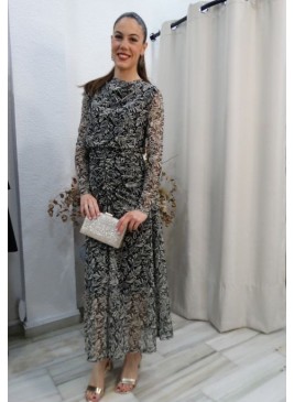 Mujer luciendo vestido largo de fiesta con estampado botánico en blanco y negro, manga de tul y detalles drapeados