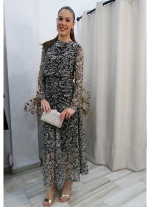 Mujer luciendo vestido largo de fiesta con estampado botánico en blanco y negro, manga de tul y detalles drapeados