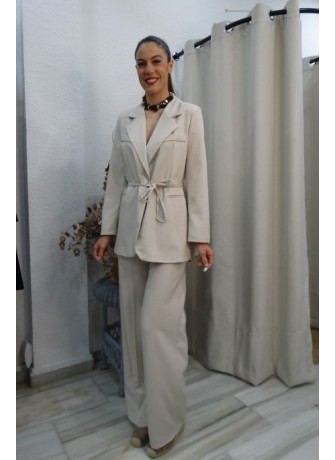 mujer posando con conjunto de blazer y pantalón de pierna ancha en tono beige, blazer anudada a la cintura