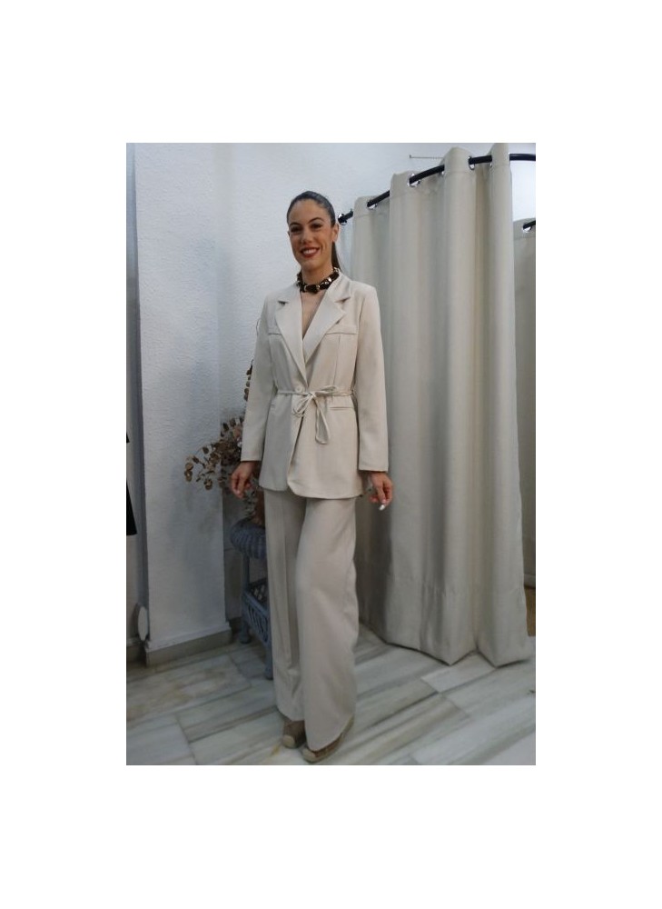 mujer posando con conjunto de blazer y pantalón de pierna ancha en tono beige, blazer anudada a la cintura