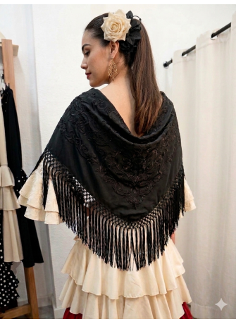 Mantón de flamenca en color negro bordado a tono y flecado a mano, colocado sobre vestido de volantes color crema