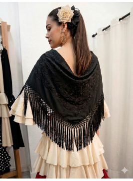 Mantón de flamenca en color negro bordado a tono y flecado a mano, colocado sobre vestido de volantes color crema