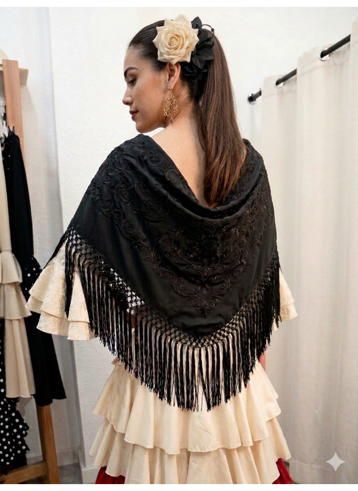 Mantón de flamenca en color negro bordado a tono y flecado a mano, colocado sobre vestido de volantes color crema