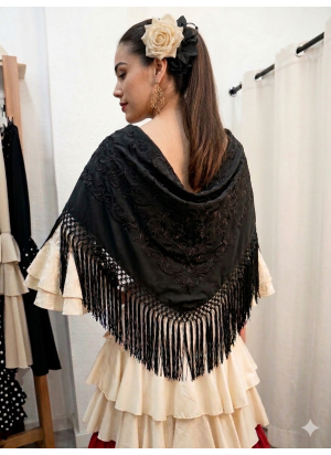 Mantón de flamenca en color negro bordado a tono y flecado a mano, colocado sobre vestido de volantes color crema